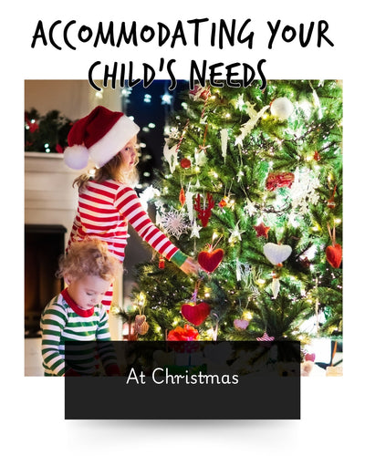 two young children sat by the Christmas tress wearing stripey pj's