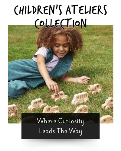 a young girl laying on the grass playing with wooden cars