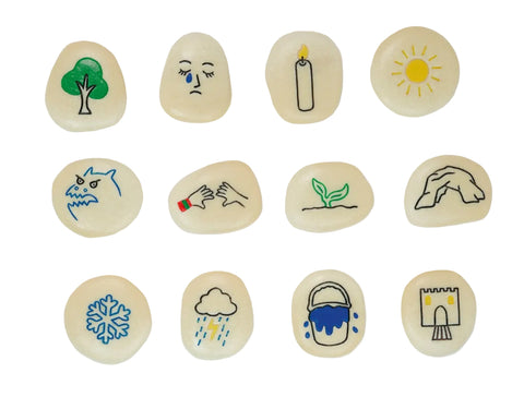 A set of twelve smooth, polished river stones arranged in a 3x4 grid on a white background. Each stone is hand-painted with a simple illustration representing a season or concept: a green tree, a sad face with a tear, a burning candle, a yellow sun, a shark, hands washing, a green sprout, a stone arch, a blue snowflake, rain with lightning, a blue bucket, and a stone castle.