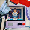 Olivia Rodrigo minifigure in a cheerleader outfit standing inside the TV screen of the LEGO Secret Storage set

