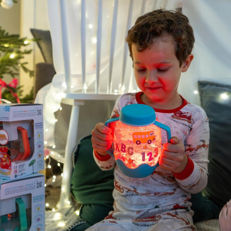 Child holding the blue Glo Pals ABC sensory jar by both handles as it glows orange
