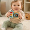 Smiling toddler holding the Busy Camera activity toy with both hand