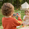 Child looking through the Busy Camera during pretend photography at an outdoor picnic