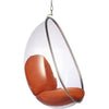 A modern hanging egg chair with a clear transparent dome shell, a silver metal frame, and orange-brown cushioned seat and backrest, suspended by a chain against a white background.