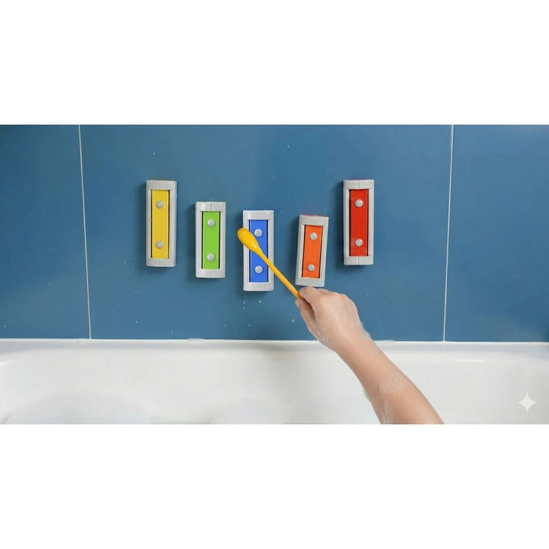 Hand playing Melody Chimes with a yellow mallet, with five bars attached to blue tiles above a bath.