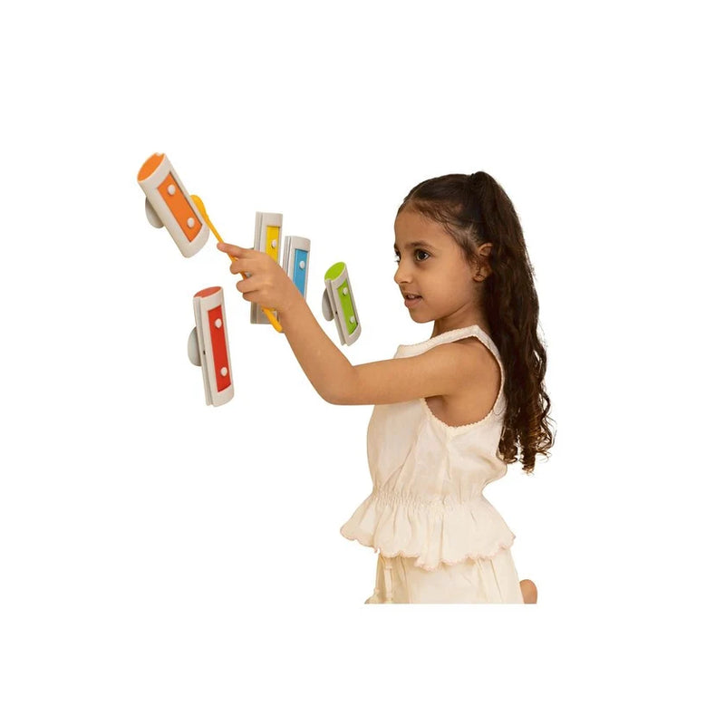 Child playing wall-mounted Melody Chimes with the yellow mallet.