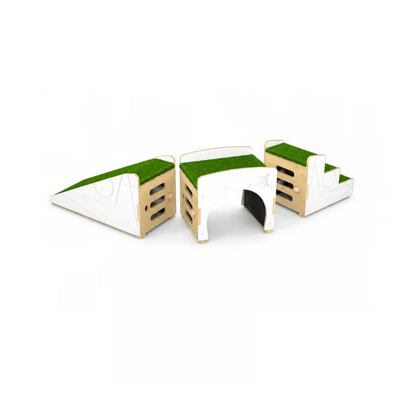 A modular wooden play structure set on a plain white background, featuring a green grass-like top surface, white side panels, and a central tunnel opening.