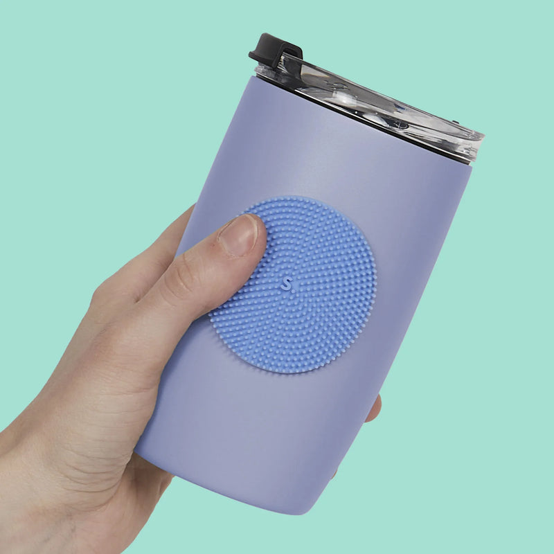 Hand holding a lilac tumbler with a blue dotted Speks Slabs sensory sticker attached

