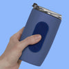 Hand holding a blue tumbler with a navy oval Speks Slabs sensory sticker attached

