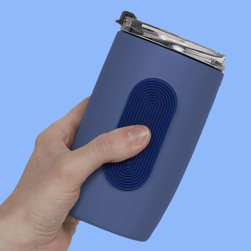 Hand holding a blue tumbler with a navy oval Speks Slabs sensory sticker attached
