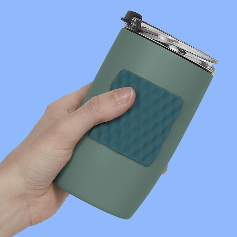Hand holding a green tumbler with a Speks Slabs Mesh Green sensory sticker attached
