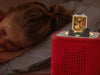 Enchanted Bedtime Stories Book Tonie on a red Toniebox beside a child resting in bed