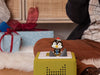 Christmas penguin Tonie on a green Toniebox beside wrapped presents