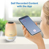 A Vtech self-recorded content device in a warm peach and white color, shown next to a woman holding a smartphone that displays the companion app. Blue text at the top reads 'Self Recorded Content with the App'.